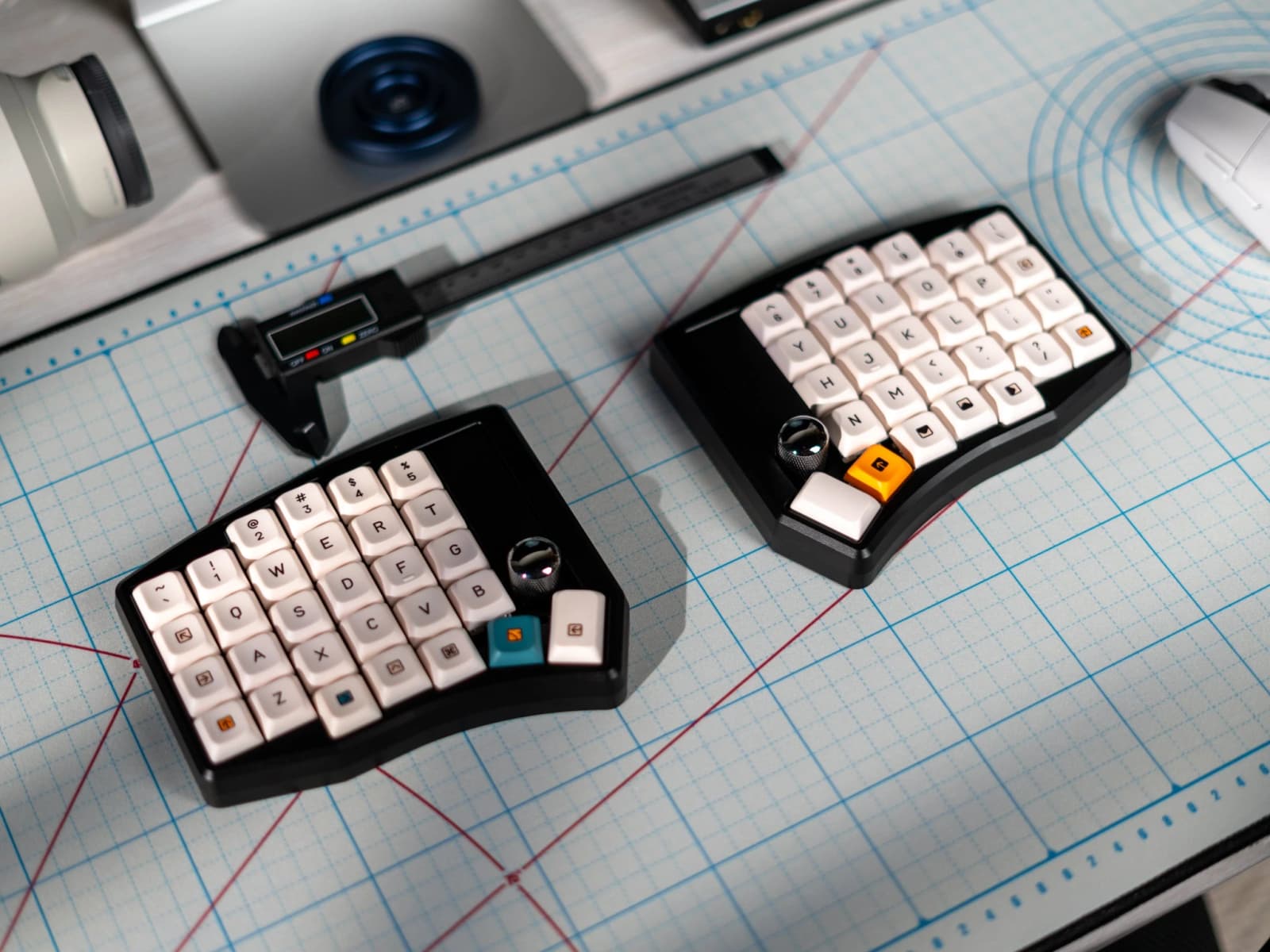 CannonKeys Link split keyboard with black cases, pale keycaps and rotary controls on a gridded work mat.