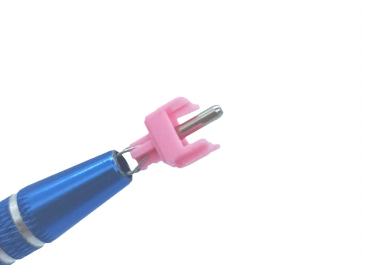 Pink Tecsee Honey Peach stem with an exposed metal center pole, held by a blue tool.