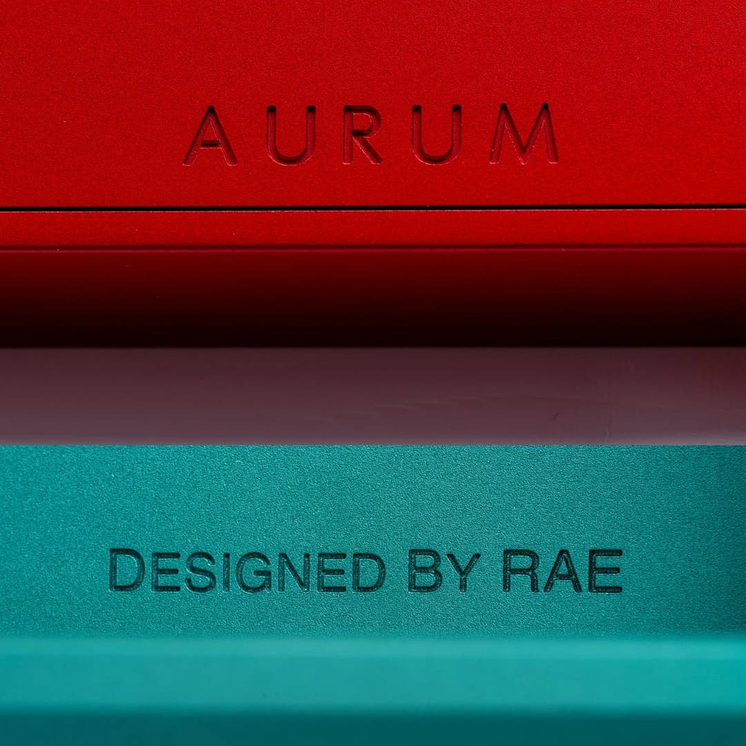 Close-up of the Aurum and Designed by RAE engravings on red and green anodised cases.