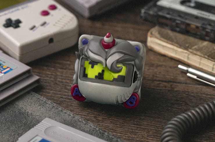 GSK DMG Unicorn artisan keycap with a gray handheld-console body, yellow-green pixel-art screen, horn and magenta buttons.