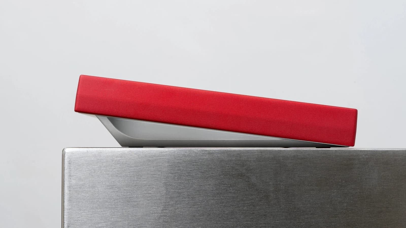 Side view of a red Chamber TKL prototype with a silver-colored bottom, showing the continuous curved underside.