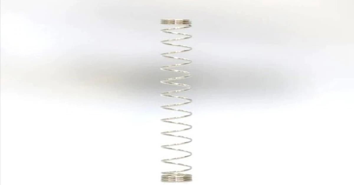 A single keyboard switch spring standing upright against a pale background.
