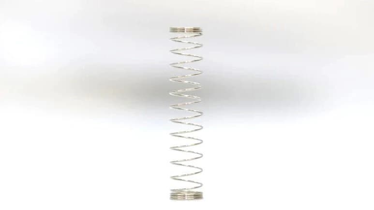 One silver-colored switch spring with a single open-coiled section between its closely wound ends.